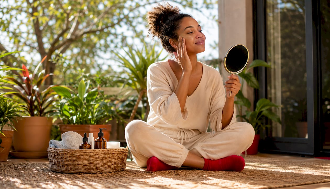 Woman applying facial oil at home with sunlight