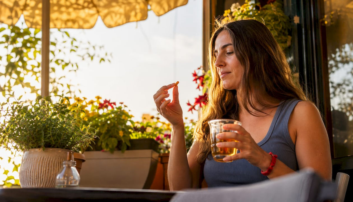 Woman taking skin supplement at kitchen table