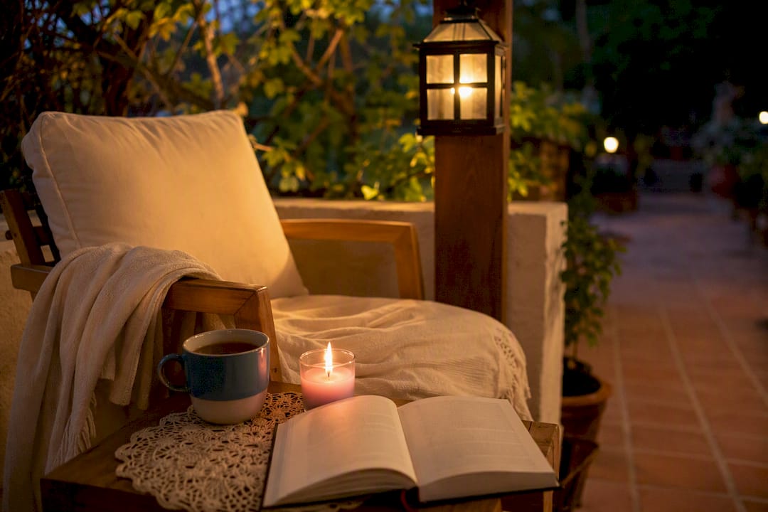 Bedside with herbal tea, book, and candle in warm light