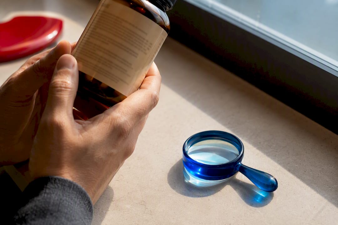 Hands inspecting an unbranded supplement bottle